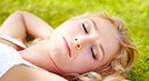 Woman laying on the grass with her eyes closed