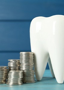 Stacks of silver coins surrounding a large ceramic tooth model