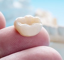 A closeup of a dental crown on a person’s finger