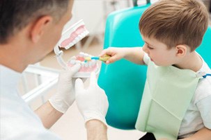 Little boy in dental chair learning to brush teeth