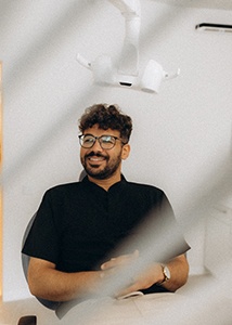Patient with black glasses smiling in treatment chair