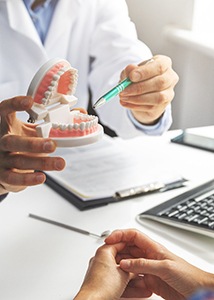 Dentist pointing to model of teeth in office
