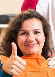 Woman in dental chair giving thumbs up