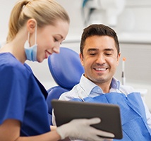 Man smiling while looking at tablet with pricing information