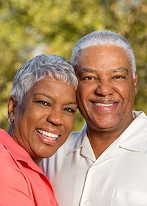 Older couple with dental implants in Jonesboro smiling outside
