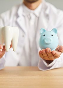 a dentist holding a model of a tooth and a piggy bank