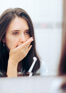 Woman covering her mouth while holding her toothbrush