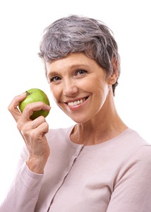 Older woman holding an apple and smiling