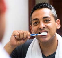 Man brushing teeth after dental implant surgery in Jonesboro