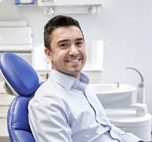 Male patient sitting in dental chair and smiling