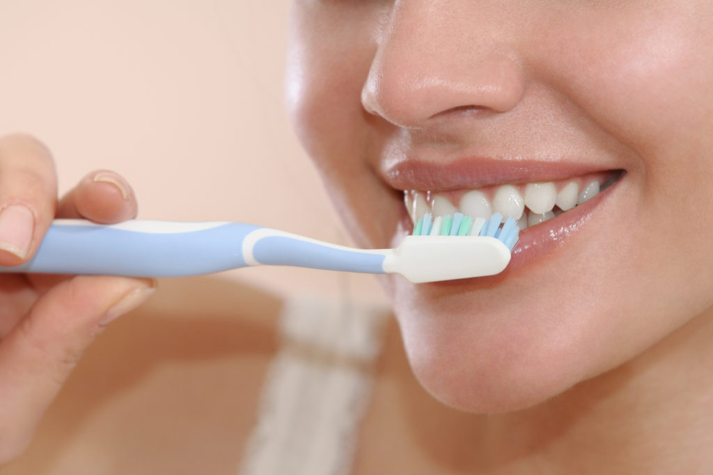 woman smiling while brushing teeth