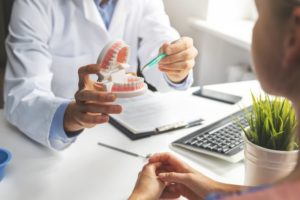 dentist showing a patient a model of a mouth