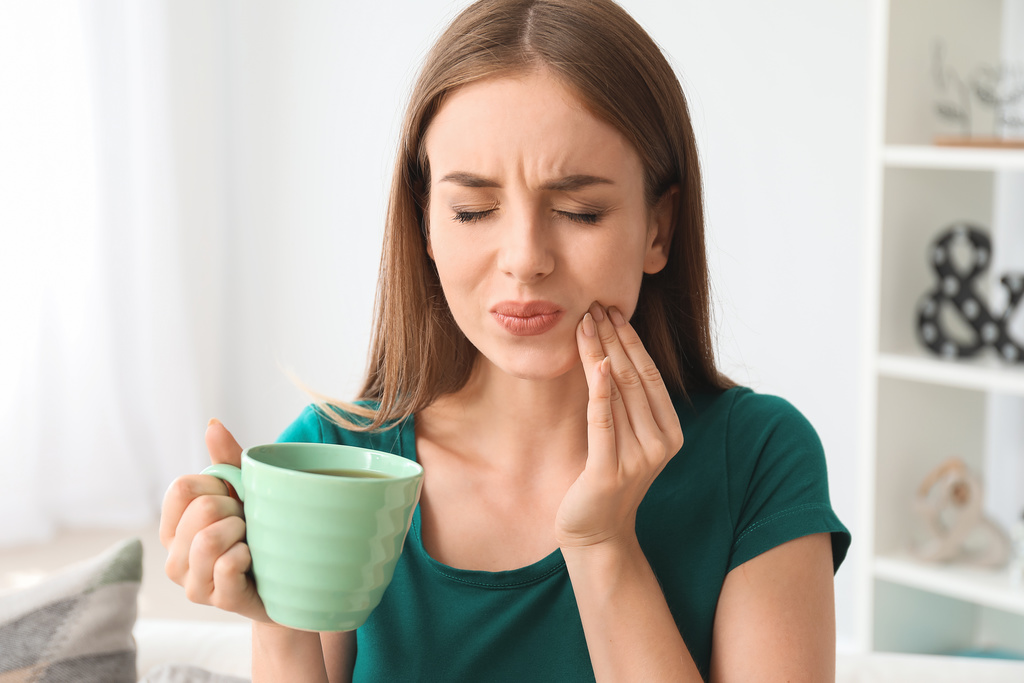 Woman needs to see a dentist in Jonesboro for sensitive teeth.