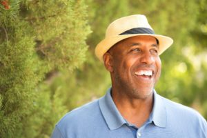 man wearing blue polo and fedora smiling with dental implants in Jonesboro