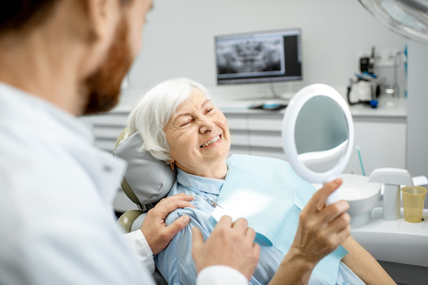 older woman smiling into a mirror at dentist's office