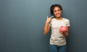 A patient holding a piggy bank and pointing towards her smile