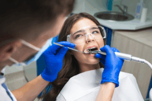 Patient opening her mouth wide as her dentist inspects her teeth